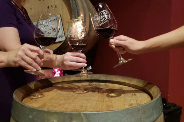 Boutier wine glasses raised above a barrel